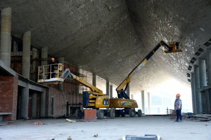 工人正加紧对主体建筑幕墙及屋面进行装饰建设