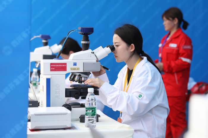 岩性分析实验比赛中，一名女选手正专注地在显微镜下观察岩屑薄片.JPG