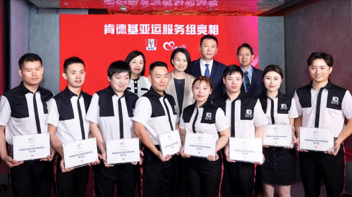 百胜中国首席执行官屈翠容（左二）、肯德基中国总经理汪涛（右二）、百胜中国首席人力资源官袁耀宗（右一）、百胜中国首席公共事务官王立志（左一）为肯德基亚运餐饮保障专项服务团队代表颁发纪念版员工证