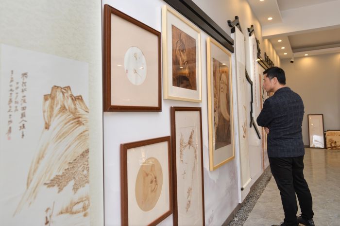 10  11月16日，内江市市中区非遗展览馆在市中区凌家镇大湾村开馆。图为游客在欣赏市级非遗烙烤画。.JPG