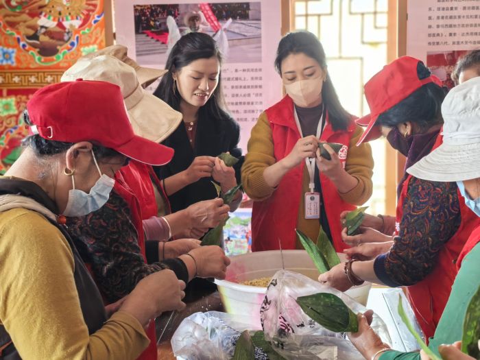 图为理塘县精神文明办组织的志愿者与社区居民一起包粽子.jpg