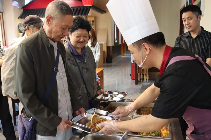 老人们有说有笑地排队取餐，食堂内饭香四溢、暖意融融。 (1)