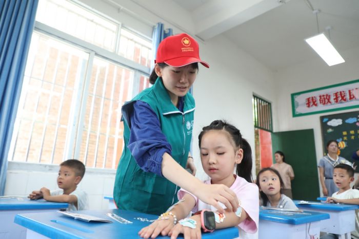 国网达州供电公司“红杜鹃”志愿者在达州市宣汉县庙安镇中心校开展“电力爱心教室”开学第一课活动，志愿者为答题学生粘贴表扬贴纸。.jpg