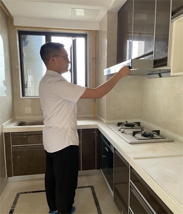 保修工程师许珂帮客户检查油烟机